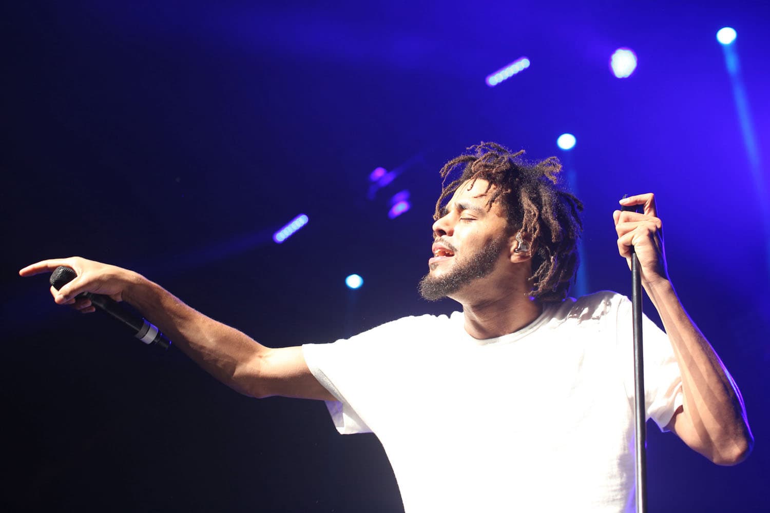Professional hip-hop concert photography of J. Cole performing on stage. Music festival performance documentation with skilled handling of stage lighting and dynamic artist movement capture.