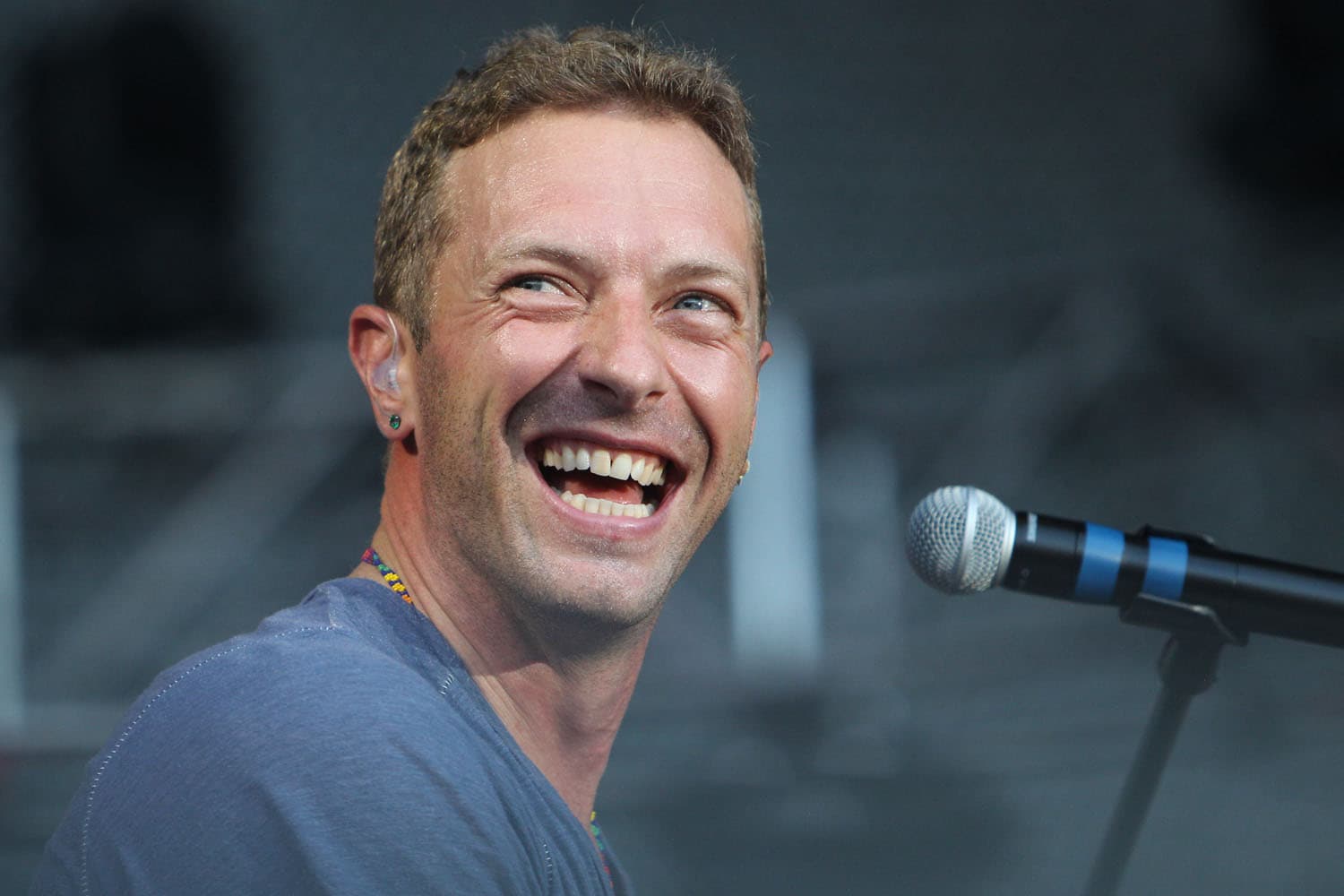Concert photography of Coldplay frontman Chris Martin performing at the piano. Stadium rock performance with dynamic lighting and large venue stage production professionally documented.