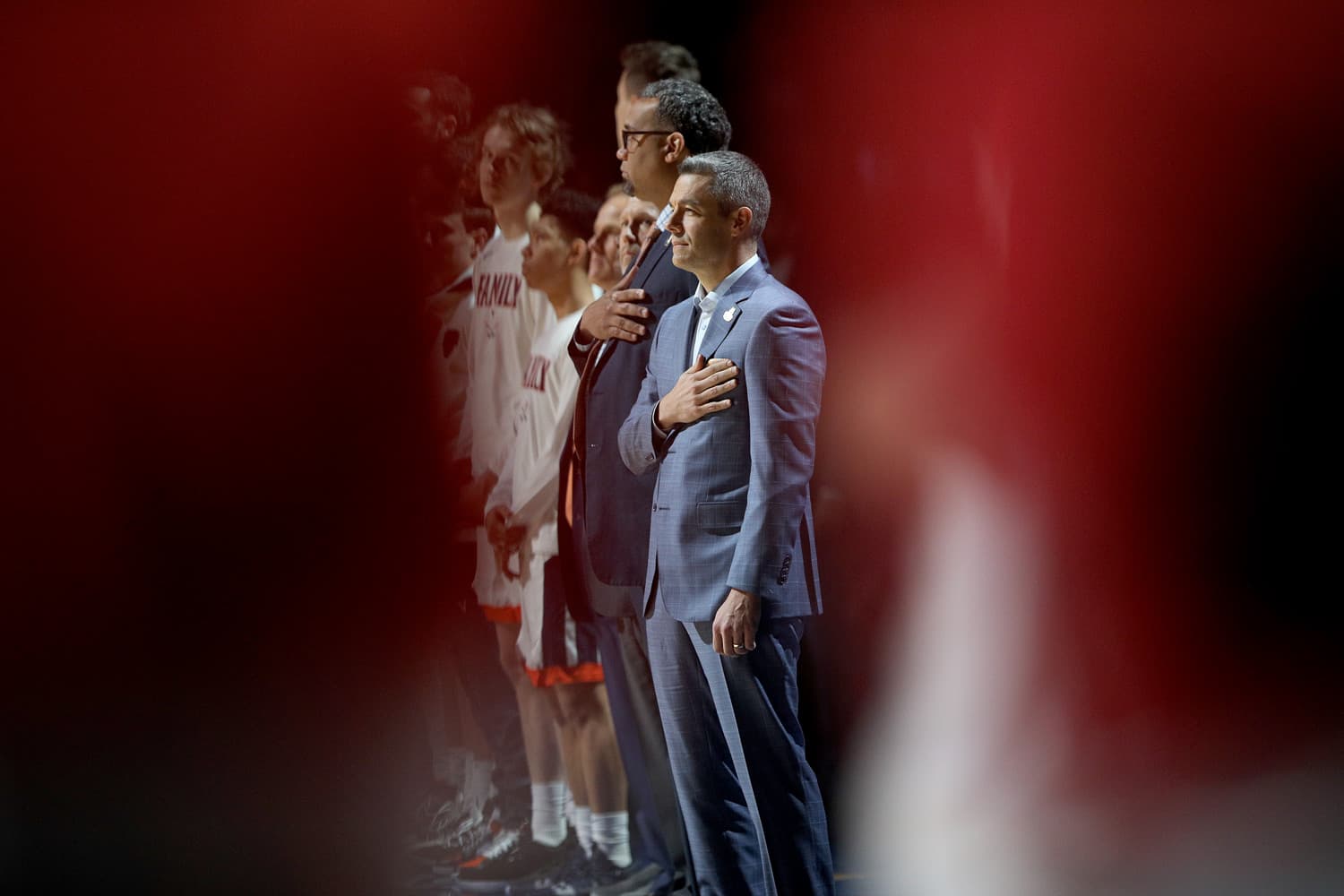Tony Bennett, head coach of the Virginia Cavaliers, standing courtside during the 2019 NCAA National Championship game against Texas Tech at U.S. Bank Stadium in Minneapolis, MN, on April 8, 2019. Dressed in a dark suit, he gestures toward his players, displaying focus and determination. The packed arena and bright overhead lights emphasize the intensity of the moment.