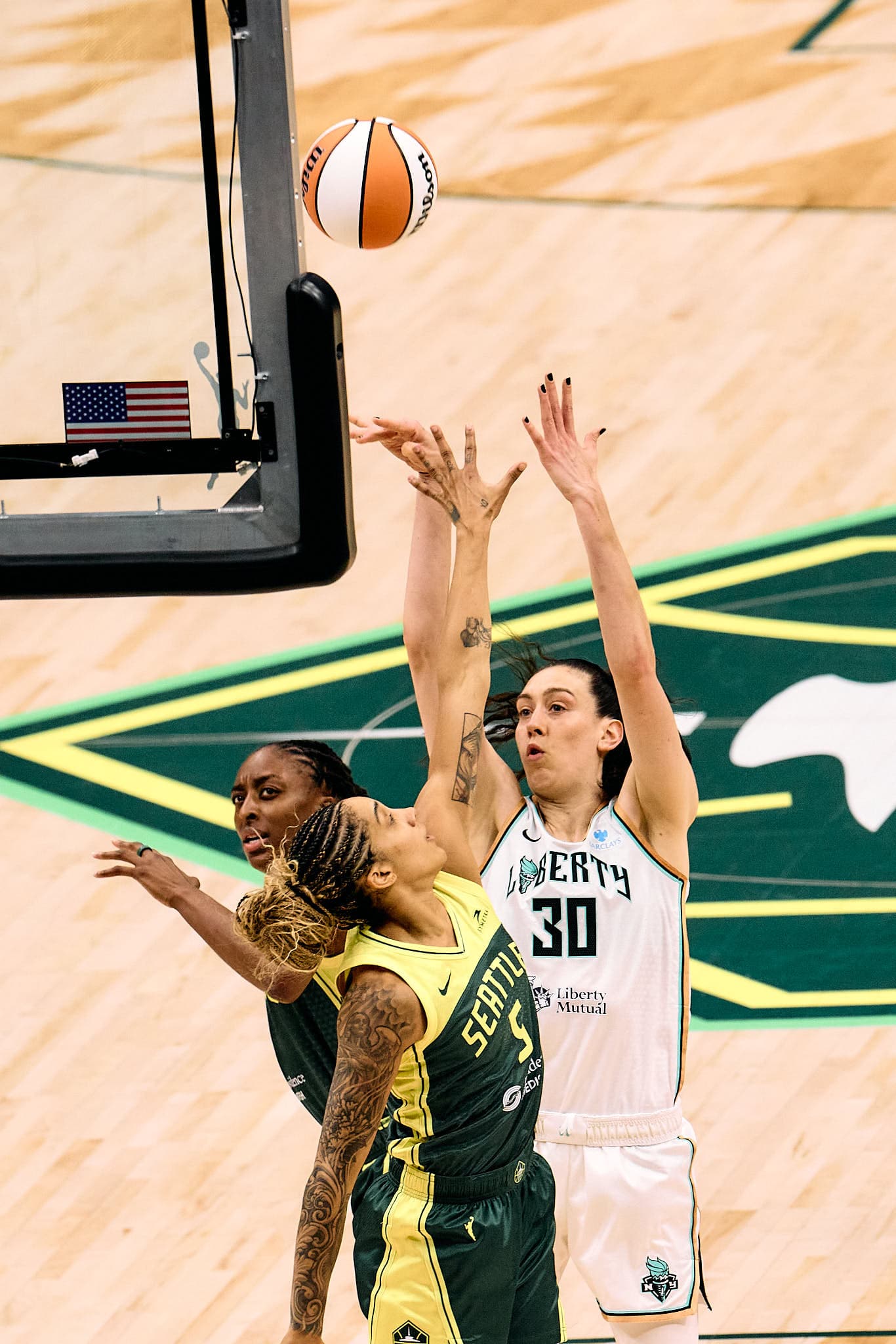 Explosive in-game moment during a WNBA matchup between the Seattle Storm and New York Liberty — players battle at the rim for a rebound with outstretched arms and mid-air intensity. A peak-action shot that captures the athleticism, emotion, and competitive edge of professional women’s basketball.