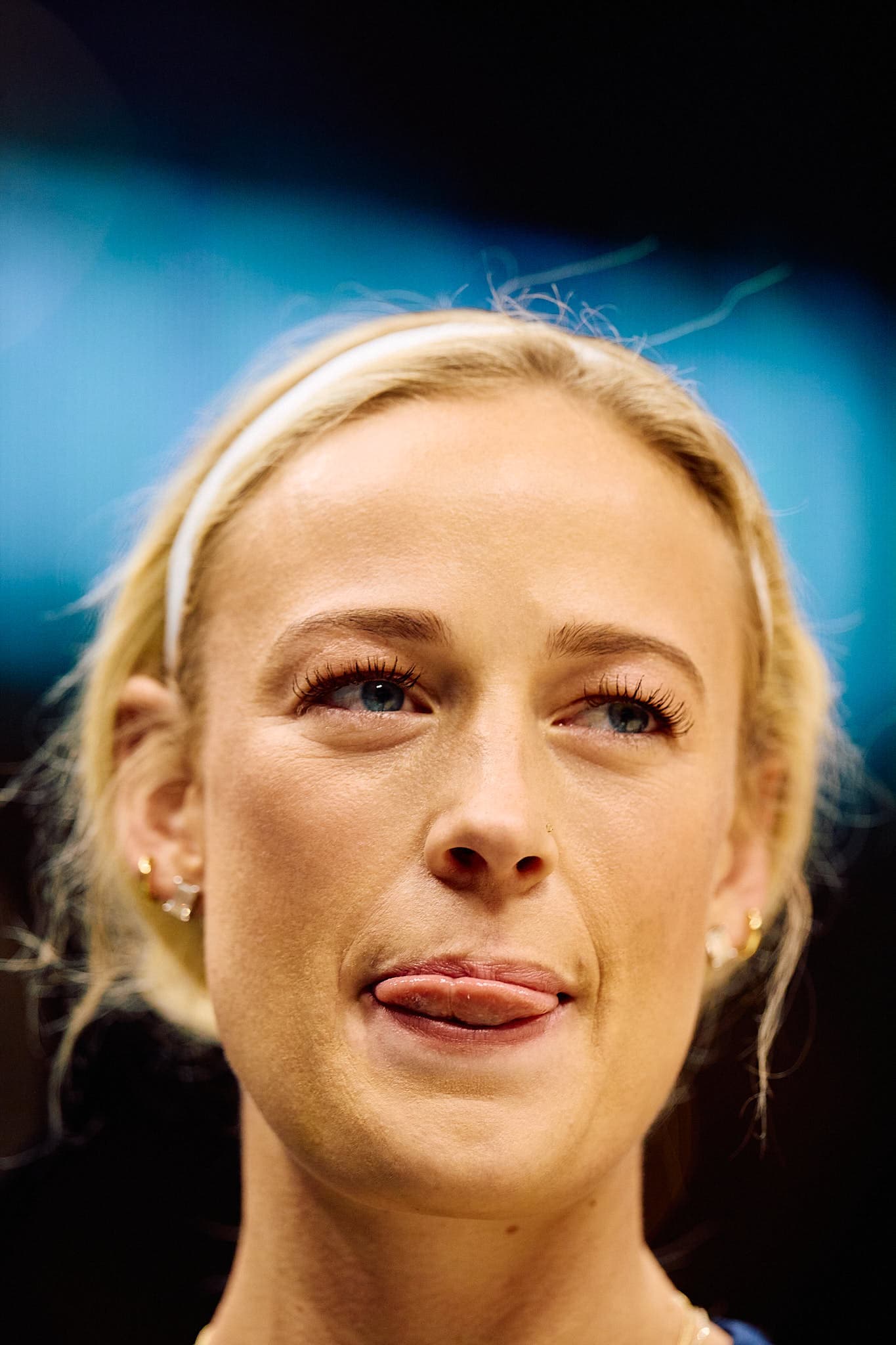 Close-up of a focused WNBA player, Sophie Cunningham, during pre-game action — highlighting intensity, personal style with layered earrings, and athletic poise. A compelling portrait of professional sports excellence, ideal for promoting elite-level sports photography.